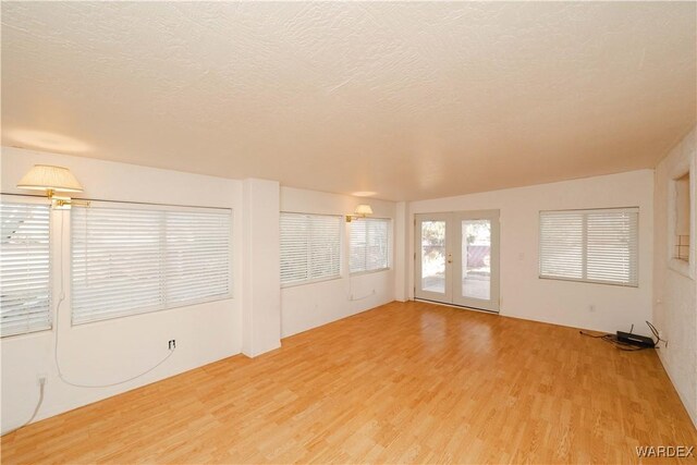 spare room with a textured ceiling, wood finished floors, and french doors