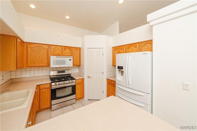 kitchen with white appliances, light tile patterned floors, decorative backsplash, light countertops, and a sink