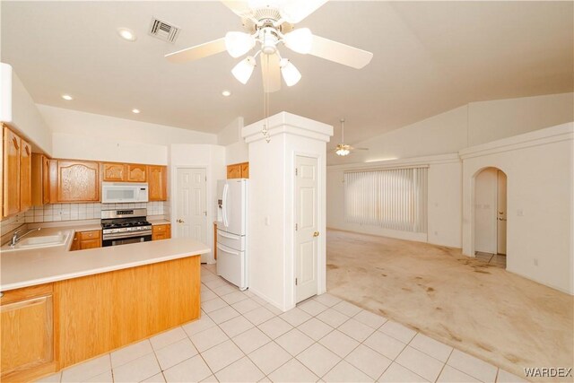 kitchen featuring a peninsula, white appliances, a sink, open floor plan, and light countertops