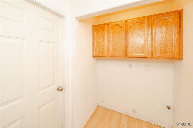 washroom featuring light wood-type flooring, cabinet space, and baseboards