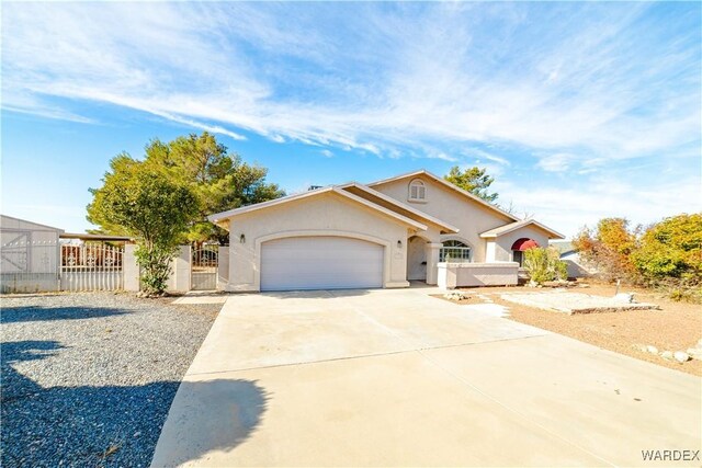 view of front facade featuring a garage, fence, concrete driveway, a gate, and stucco siding