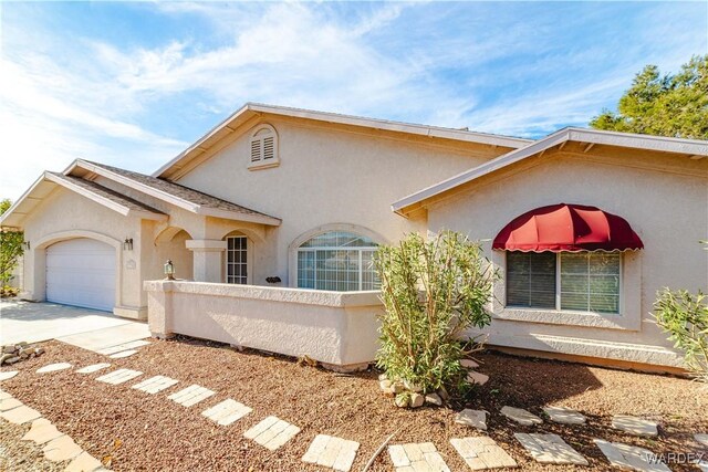 view of front of house with a garage, driveway, and stucco siding