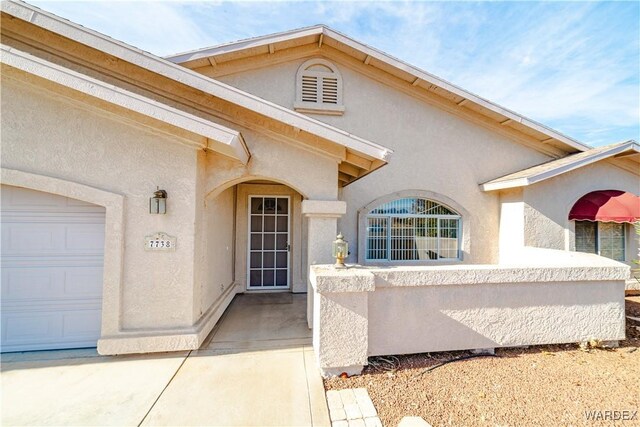 doorway to property featuring a garage and stucco siding