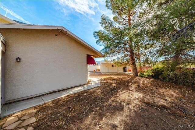 view of side of home with fence and stucco siding