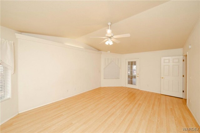 empty room featuring lofted ceiling, light wood finished floors, and a ceiling fan