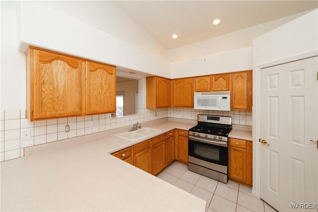 kitchen featuring a sink, white microwave, light countertops, and stainless steel range with gas stovetop