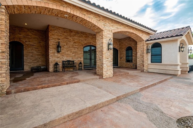 entrance to property with stucco siding, a tile roof, and a patio