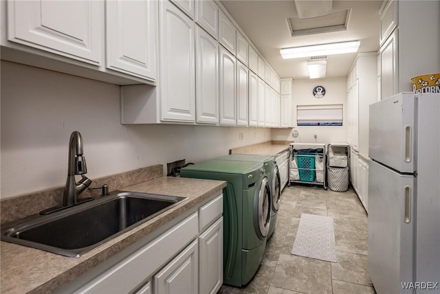 clothes washing area featuring cabinet space, attic access, separate washer and dryer, and a sink