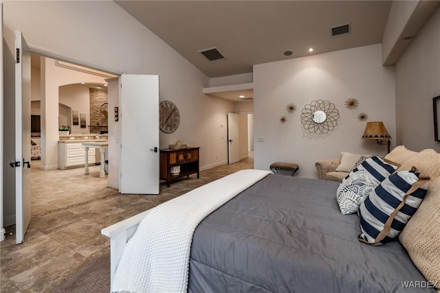 bedroom featuring arched walkways, visible vents, lofted ceiling, and ensuite bath