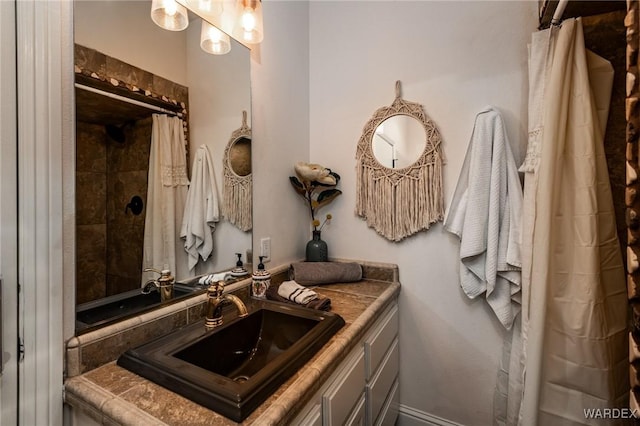 full bath featuring tiled shower and vanity