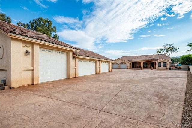 view of side of home featuring a garage, a tile roof, and stucco siding