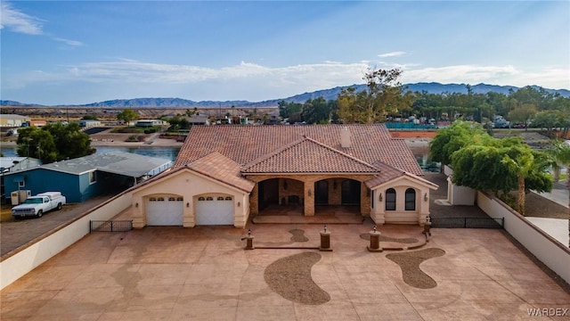 mediterranean / spanish home featuring driveway, an attached garage, a tile roof, and a mountain view