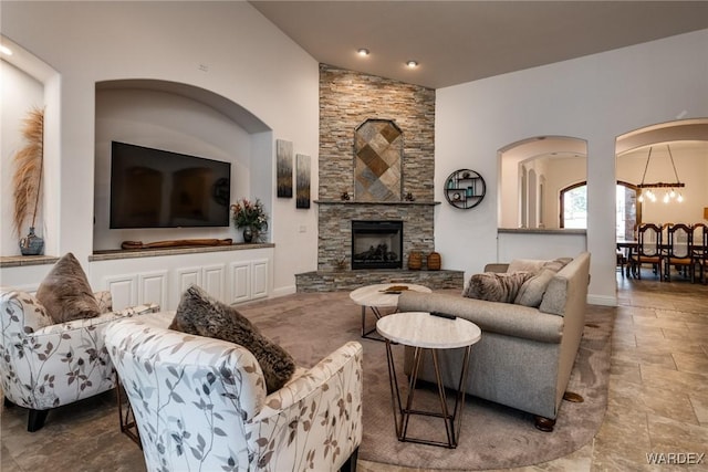 living room featuring baseboards, vaulted ceiling, and a stone fireplace