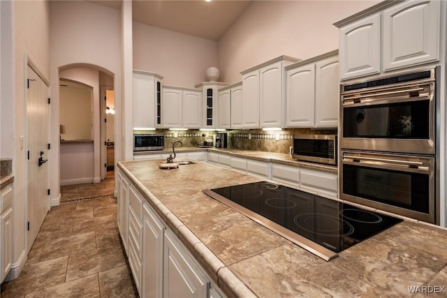 kitchen featuring stainless steel appliances, white cabinetry, glass insert cabinets, and a sink