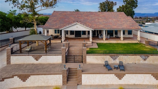 view of front of home with fence private yard, a gazebo, a tiled roof, stucco siding, and a patio area