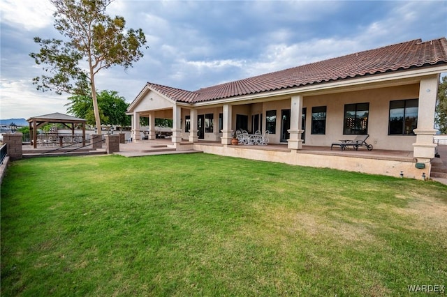 back of house featuring stucco siding, a yard, and a gazebo