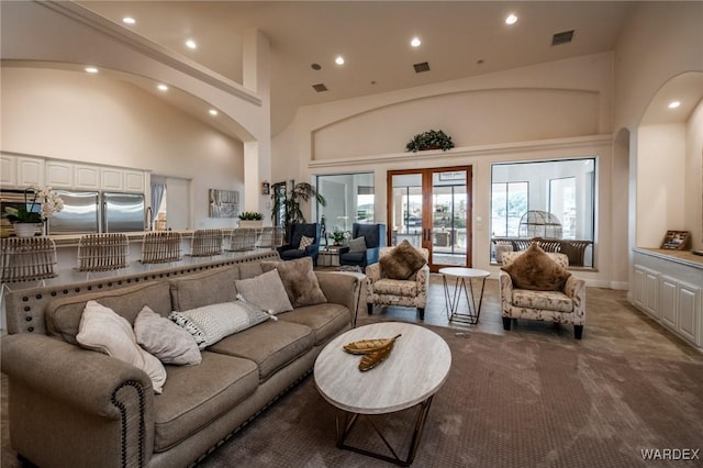 carpeted living room featuring recessed lighting, french doors, visible vents, and a high ceiling