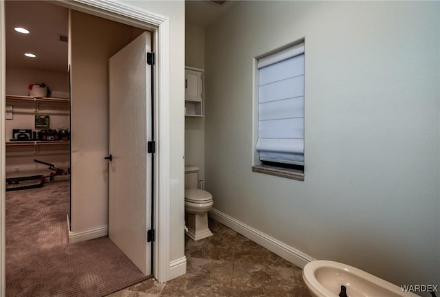 bathroom featuring toilet, baseboards, a bidet, and recessed lighting