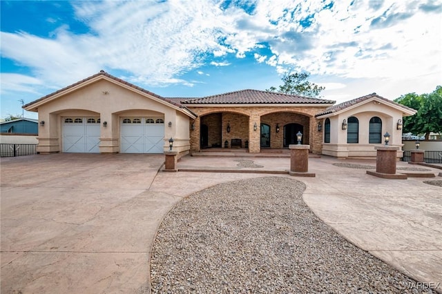 mediterranean / spanish-style house with concrete driveway, a tiled roof, an attached garage, fence, and stucco siding