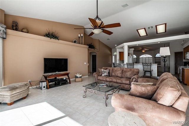 living room featuring arched walkways, light tile patterned flooring, ceiling fan, high vaulted ceiling, and baseboards