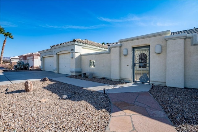 mediterranean / spanish house with driveway, a tiled roof, a garage, and stucco siding