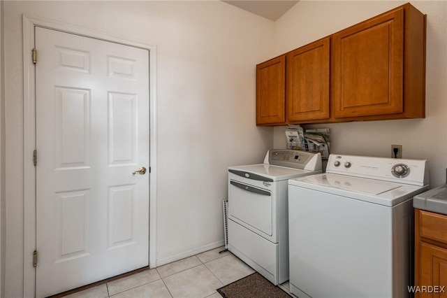 laundry area with light tile patterned floors, cabinet space, baseboards, and separate washer and dryer