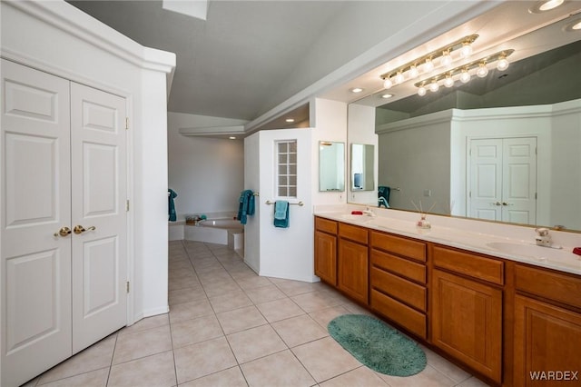 bathroom with vaulted ceiling, double vanity, a closet, and tile patterned floors