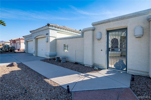 view of side of home with a garage, driveway, a tiled roof, and stucco siding