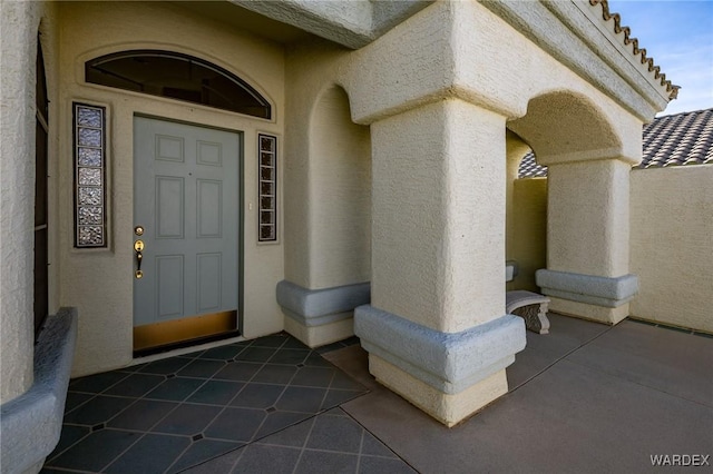 view of exterior entry featuring a tiled roof and stucco siding