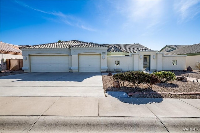 view of front facade with concrete driveway, a tiled roof, an attached garage, and stucco siding