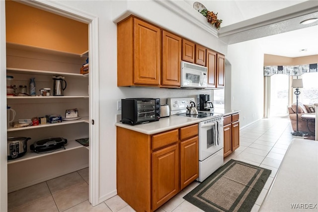 kitchen with white appliances, a toaster, light tile patterned floors, brown cabinets, and light countertops