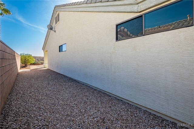 view of side of home featuring fence and stucco siding