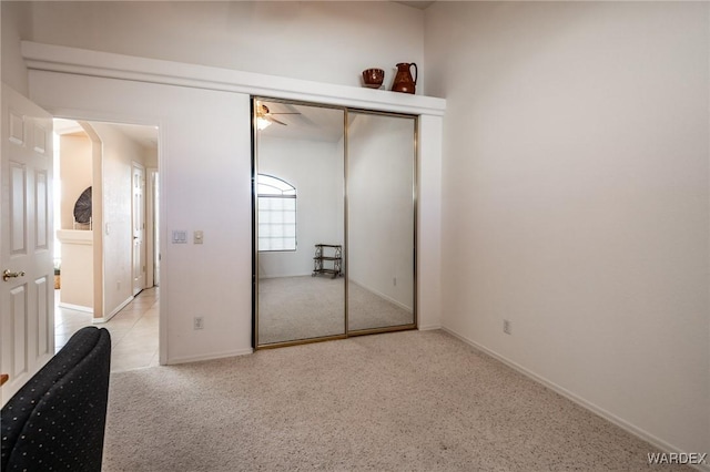 unfurnished bedroom with arched walkways, a closet, light carpet, and baseboards