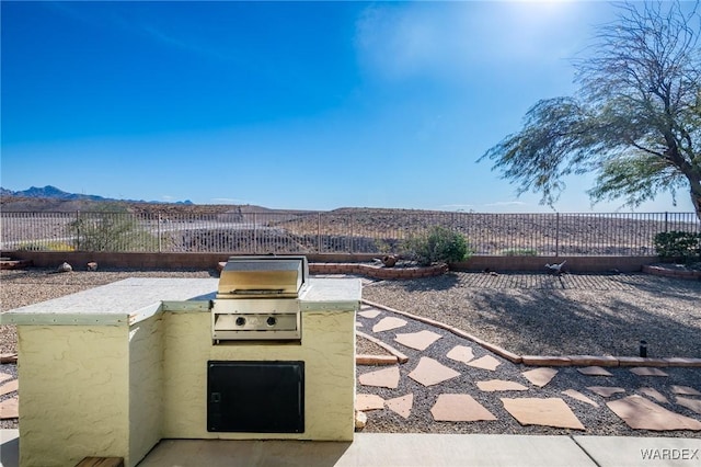 view of patio with area for grilling, a fenced backyard, and a mountain view