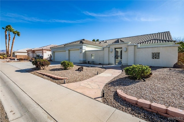 mediterranean / spanish-style house with a garage, a tile roof, concrete driveway, and stucco siding