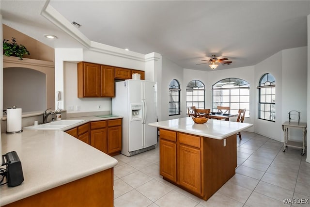 kitchen featuring a peninsula, a sink, visible vents, light countertops, and white fridge with ice dispenser