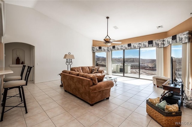 living room featuring arched walkways, visible vents, light tile patterned flooring, ceiling fan, and high vaulted ceiling