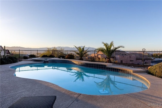 pool at dusk with a fenced in pool, a mountain view, and fence