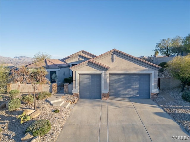 mediterranean / spanish house featuring stucco siding, a gate, fence, a garage, and driveway