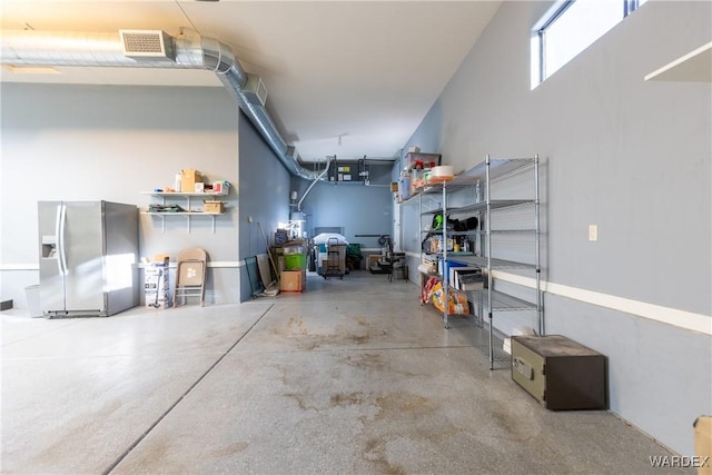 garage featuring visible vents and stainless steel refrigerator with ice dispenser