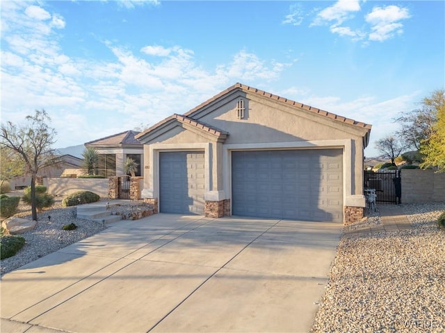 mediterranean / spanish house with an attached garage, driveway, a gate, and stucco siding