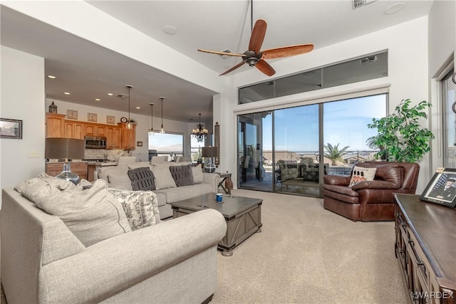 living room featuring ceiling fan with notable chandelier, visible vents, and recessed lighting