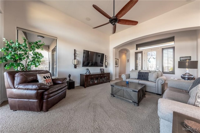 carpeted living area featuring arched walkways and ceiling fan