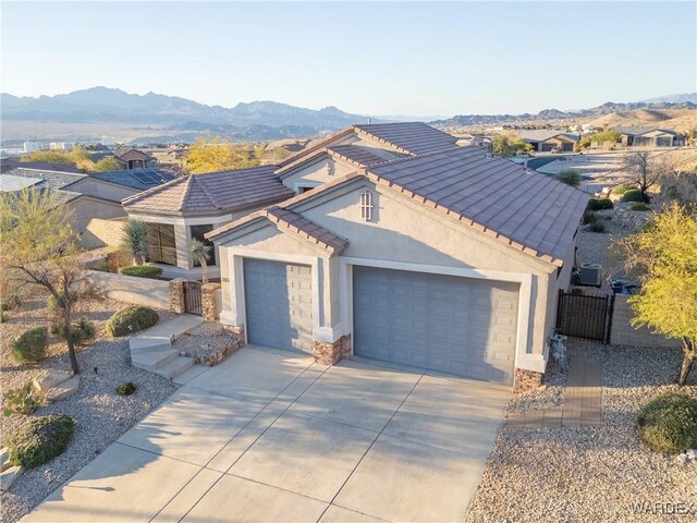 view of front of property with a mountain view, a garage, a tile roof, concrete driveway, and stucco siding