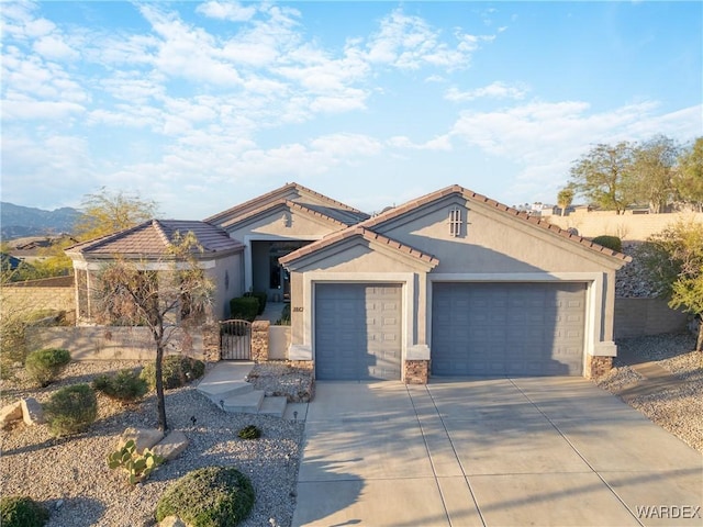 mediterranean / spanish house with an attached garage, fence, a tile roof, driveway, and stucco siding