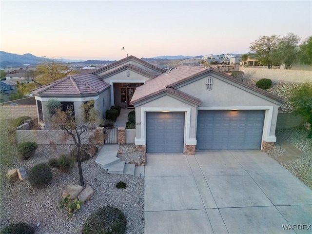 mediterranean / spanish-style home with a fenced front yard, stucco siding, a gate, a garage, and driveway