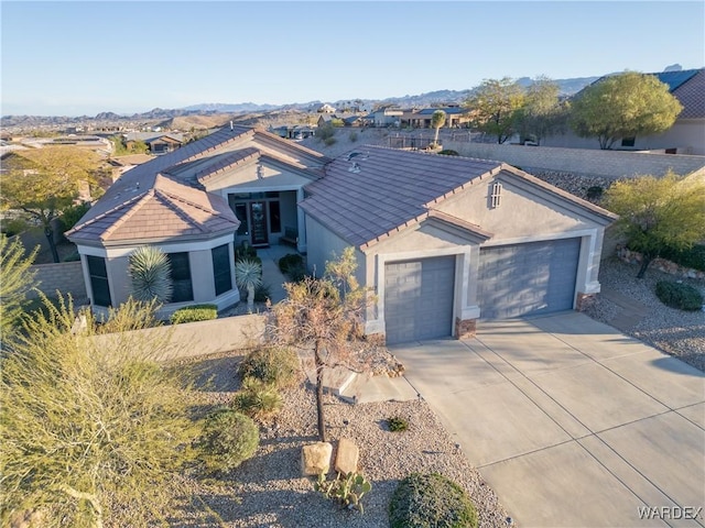 view of front of home with a garage, driveway, a tiled roof, and stucco siding