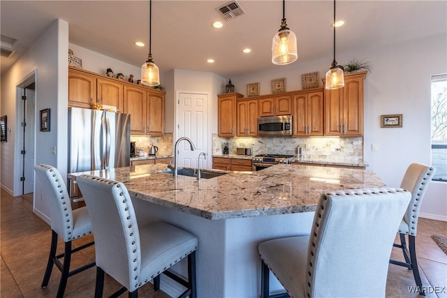 kitchen featuring a breakfast bar, stainless steel appliances, visible vents, backsplash, and a sink