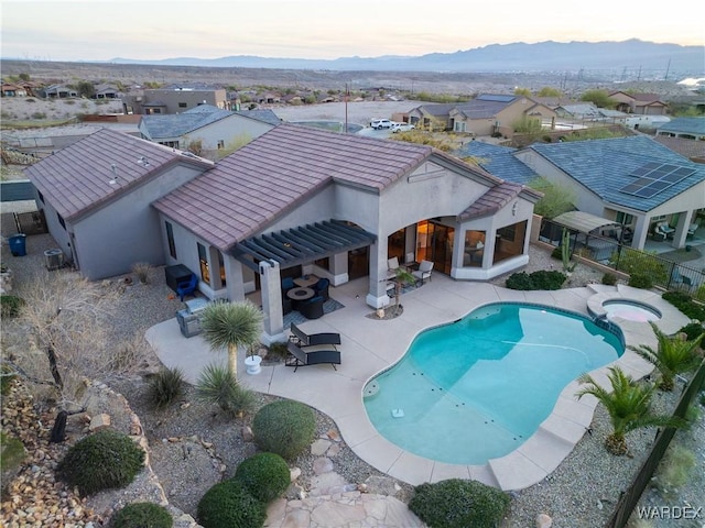 view of swimming pool featuring a residential view, a pool with connected hot tub, a patio, and a mountain view