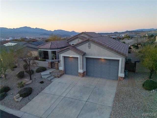 view of front of house with a garage, concrete driveway, a tiled roof, a mountain view, and stucco siding